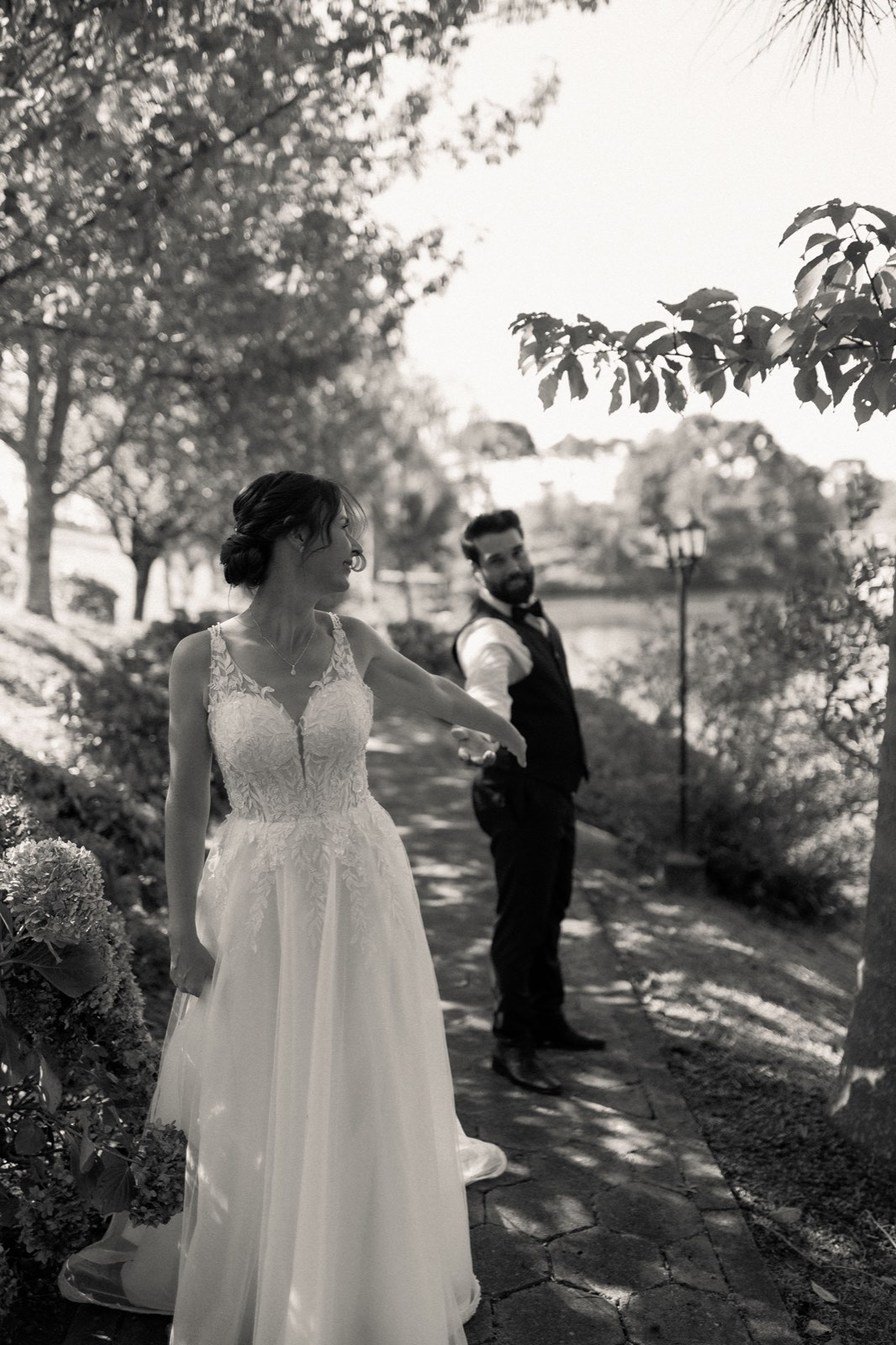 A bride and groom reaching for each other on a garden path during their first look